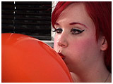 Xev inflates a balloon with her eyes crossed